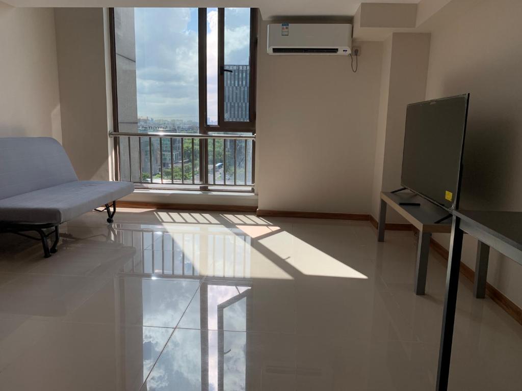 an empty room with a television and a balcony at iNestin Shanghai Apt Waigaoqiao in Shanghai