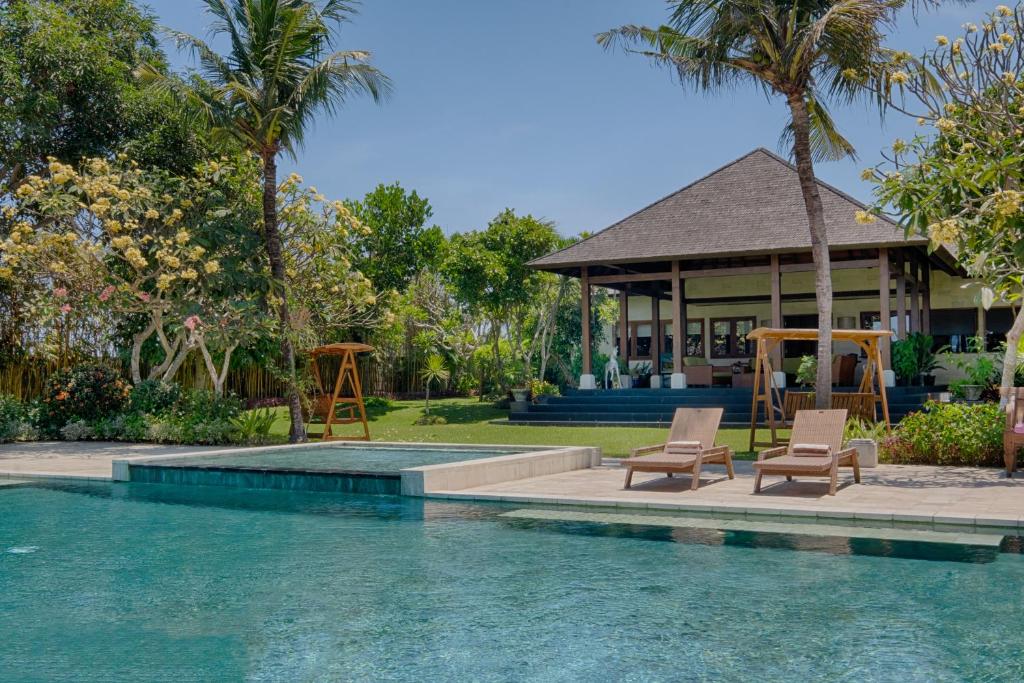 a swimming pool with two chairs and a house at Kutus Kutus Ketewel Villa in Gianyar