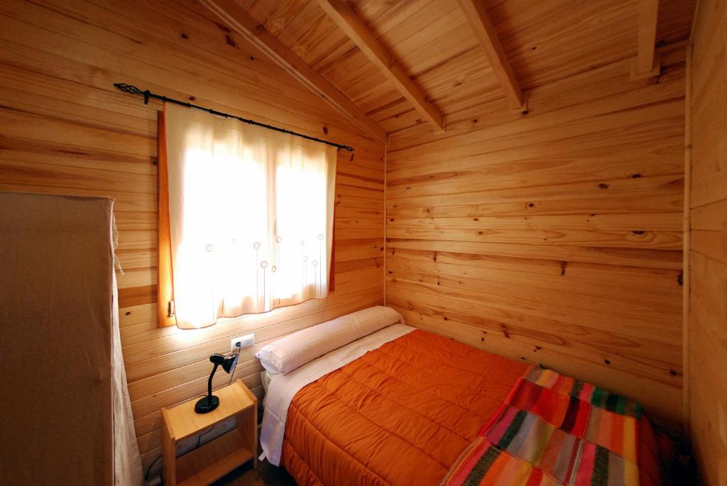 1 dormitorio con 1 cama en una habitación de madera en Cabañas del Cortino, en Monleras