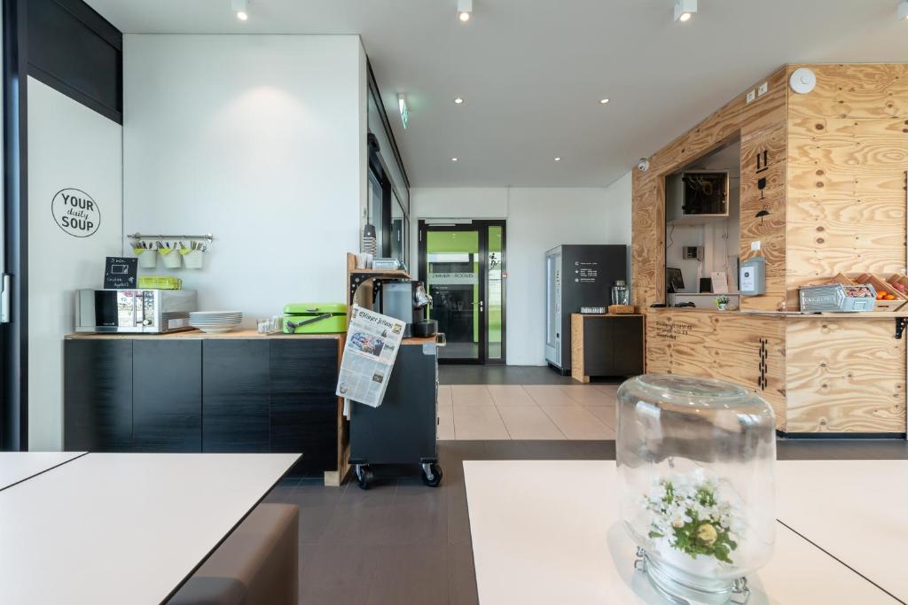 a kitchen with a counter with flowers in a vase on a table at a2 HOTELS Denkendorf - Airport & Messe in Denkendorf