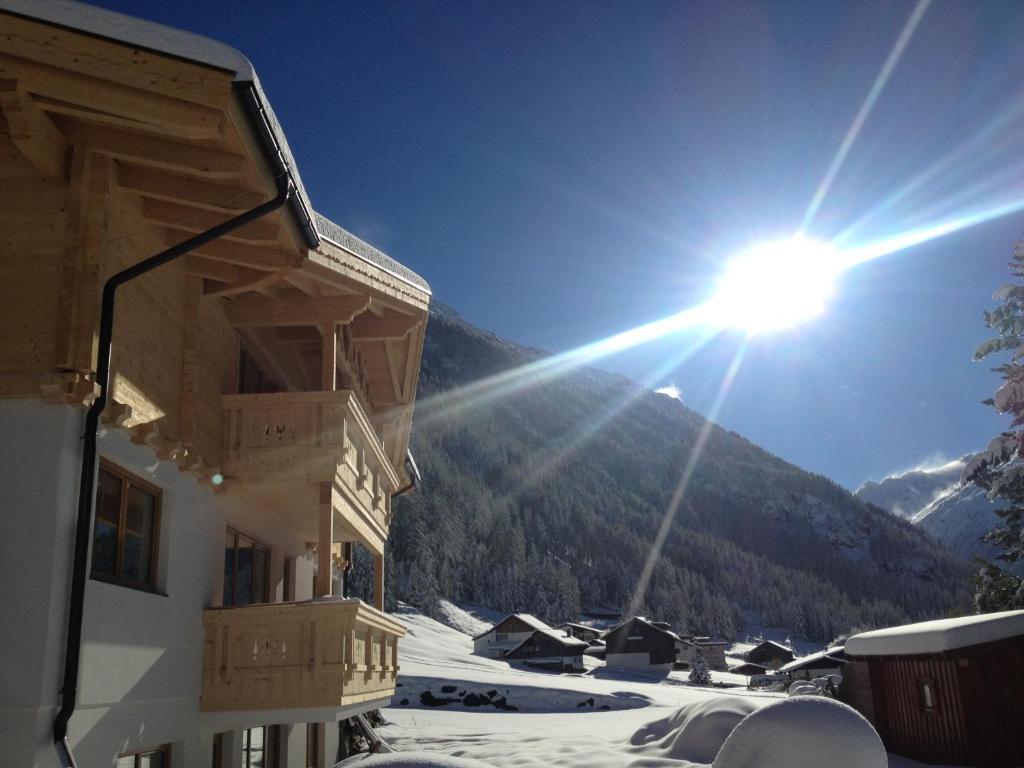 un sol brilla en el cielo sobre una montaña cubierta de nieve en Santerhof, en Sölden