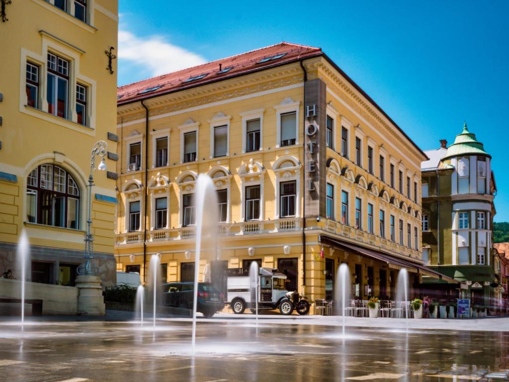 a building with a fountain in front of it at Hotel Evropa in Celje