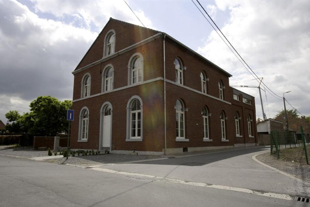 a large brick building with white windows on a street at De Oude School 4 pers app in Visé