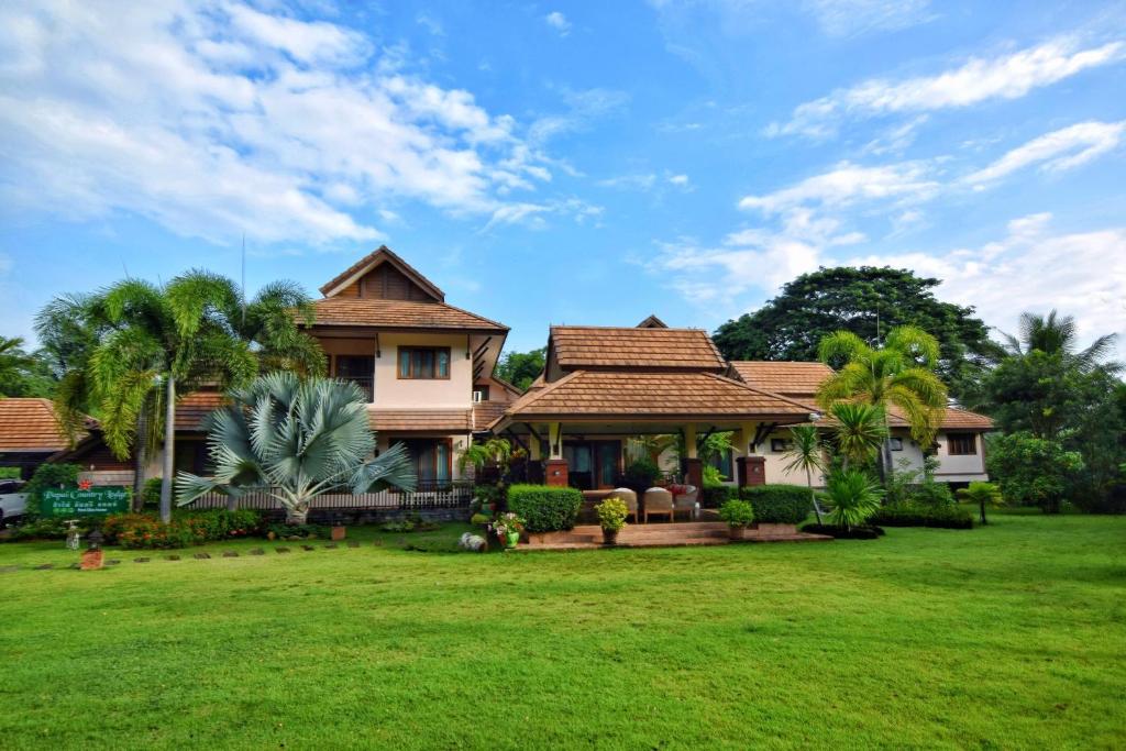una casa con un césped verde delante de ella en Papai Country Lodge SHA, en Ban Mae Pong