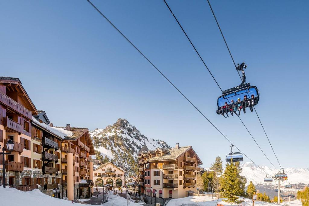 a ski lift with people on it in front of buildings at ALPS les ARCS 1950 Prince des Cimes, ski-in out,swimming pool, sauna, shoes dryer in Bourg-Saint-Maurice