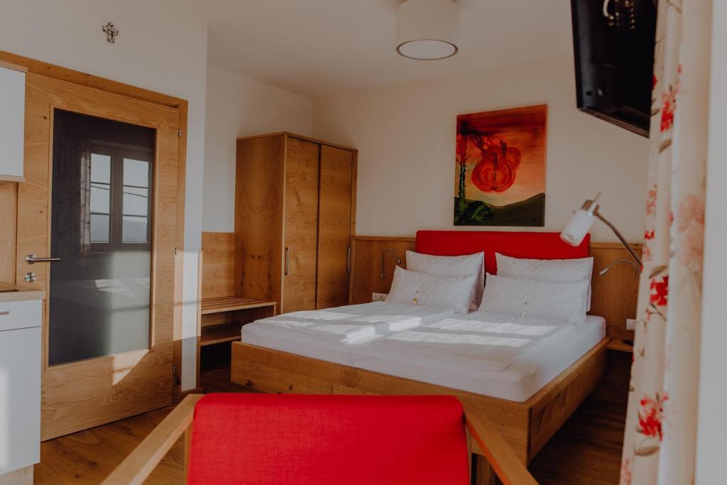 a bedroom with a bed with a red headboard and a red chair at Winzerhaus am Gamlitzberg in Gamlitz