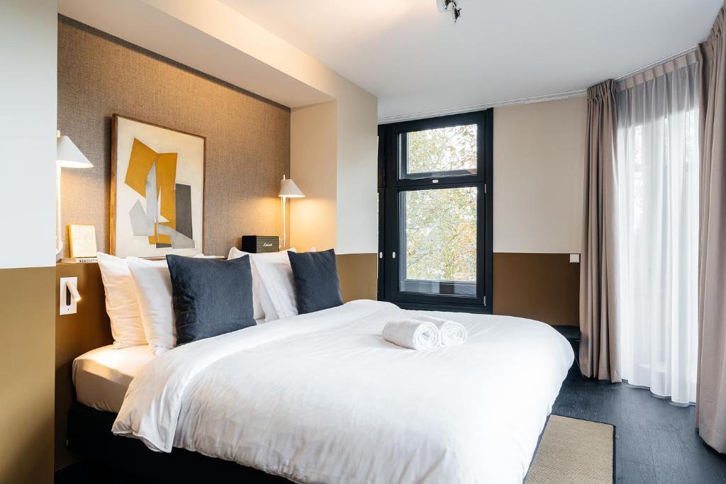 een slaapkamer met een groot wit bed en een raam bij The Hunfeld in Utrecht