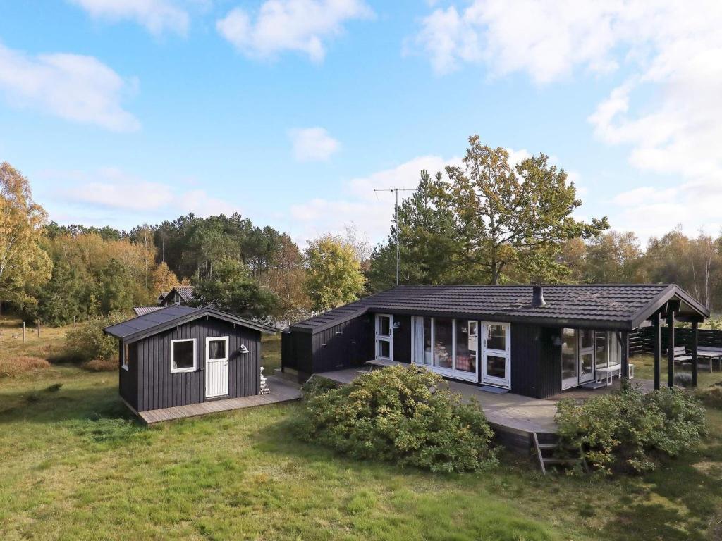 una pequeña casa negra con un porche en un campo en 4 person holiday home in L s en Læsø