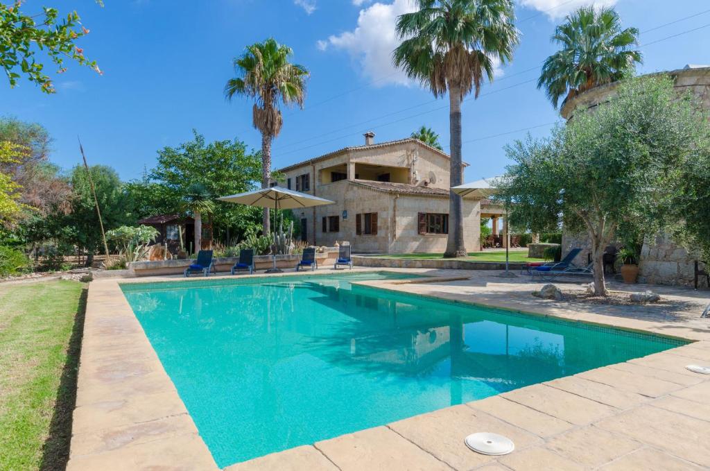 a swimming pool in front of a house with palm trees at Sa Resclosa in Sa Pobla