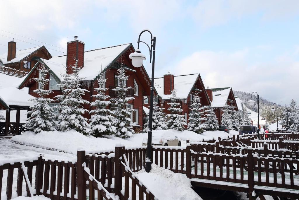 a house covered in snow in front of a fence at Bukovel Hotel in Bukovel