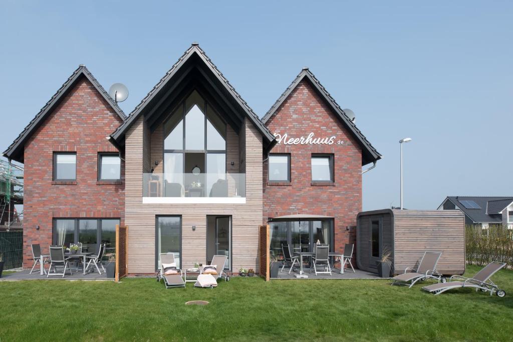 ein großes Backsteinhaus mit Stühlen und Tischen im Hof in der Unterkunft Meerhuus mit Sauna in Carolinensiel