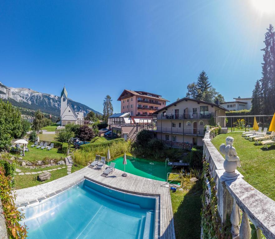 ein Schwimmbad in einem Hof neben einem Haus in der Unterkunft Hotel Cresta in Flims