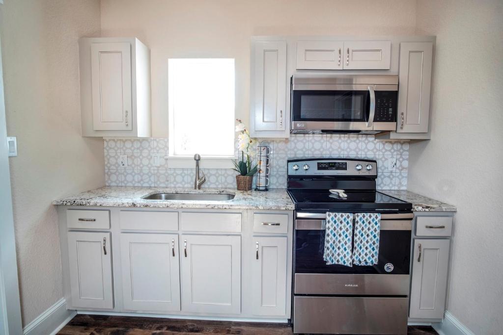 a kitchen with white cabinets and a stove and a sink at Beautiful Guest House on New Built Home Near Downtown in San Antonio