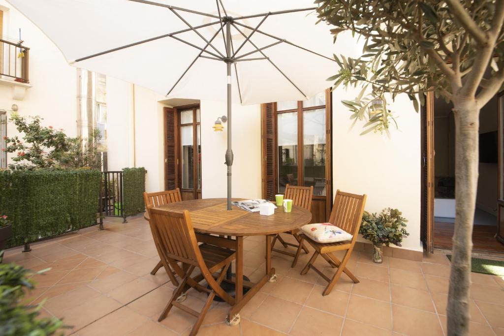 einen Holztisch und Stühle mit Sonnenschirm auf einer Terrasse in der Unterkunft Santa Clara by Oldtown Apartments in San Sebastián
