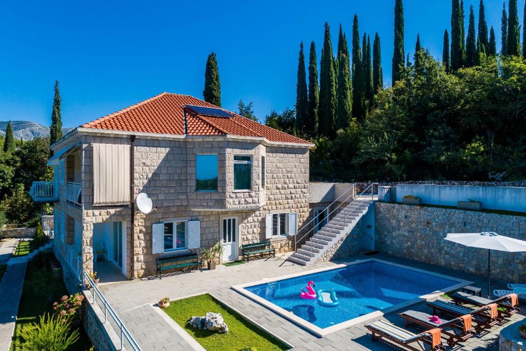 a villa with a swimming pool in front of a house at Villa Oasis Cypress in Čilipi