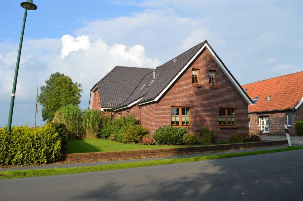 a brick house with a black roof on a street at Ferienwohnung Schmidt, 95131 in Rhauderfehn