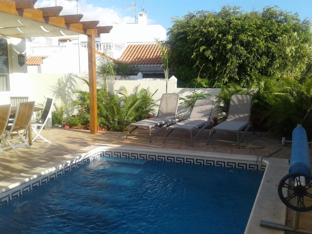a swimming pool with chairs next to a house at La Caleta Luxury Seaside Villa with 3 Bedrooms and Private Pool in Adeje