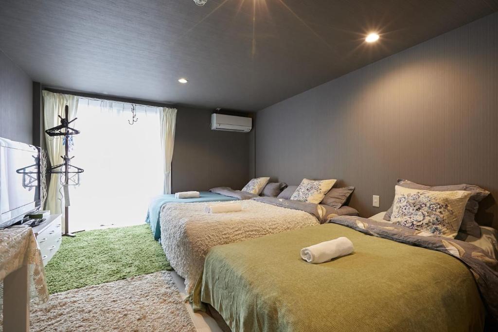 a bedroom with two beds and a tv and a window at Akabane TK Building 102 in Tokyo