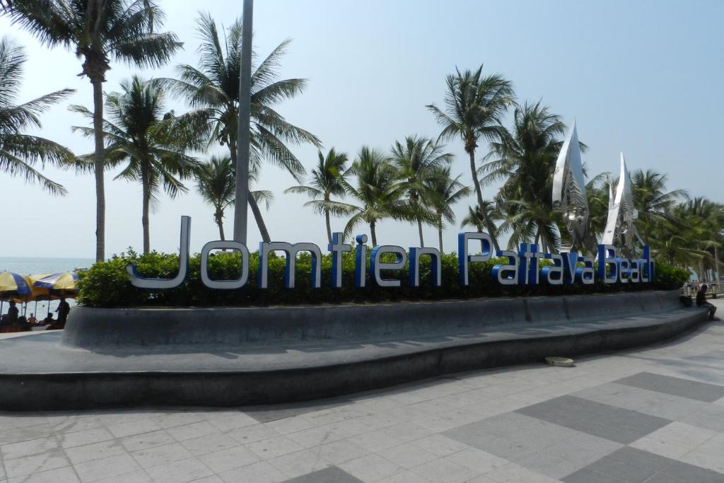 a sign for a hotel with palm trees in the background at NEOcondo @ PATTAYA in Jomtien Beach