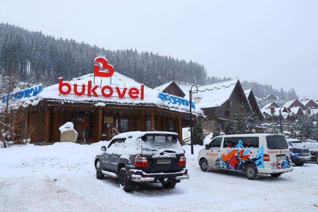 two cars parked in the snow in front of a building at Bukovel Hotel in Bukovel
