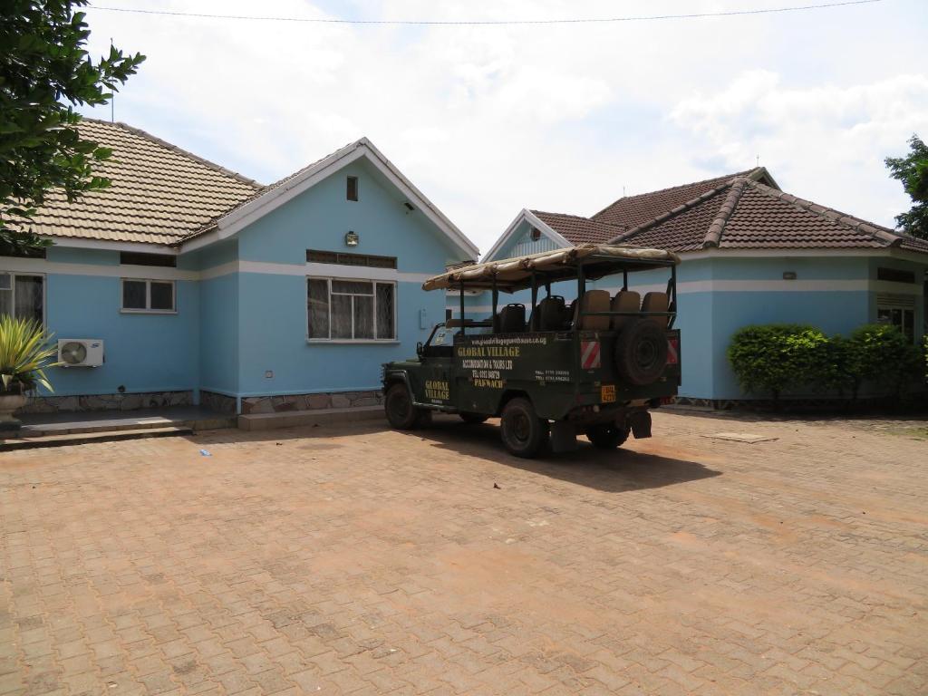 un jeep verde estacionado frente a una casa azul en Global Village Hotel, en Pakwach East