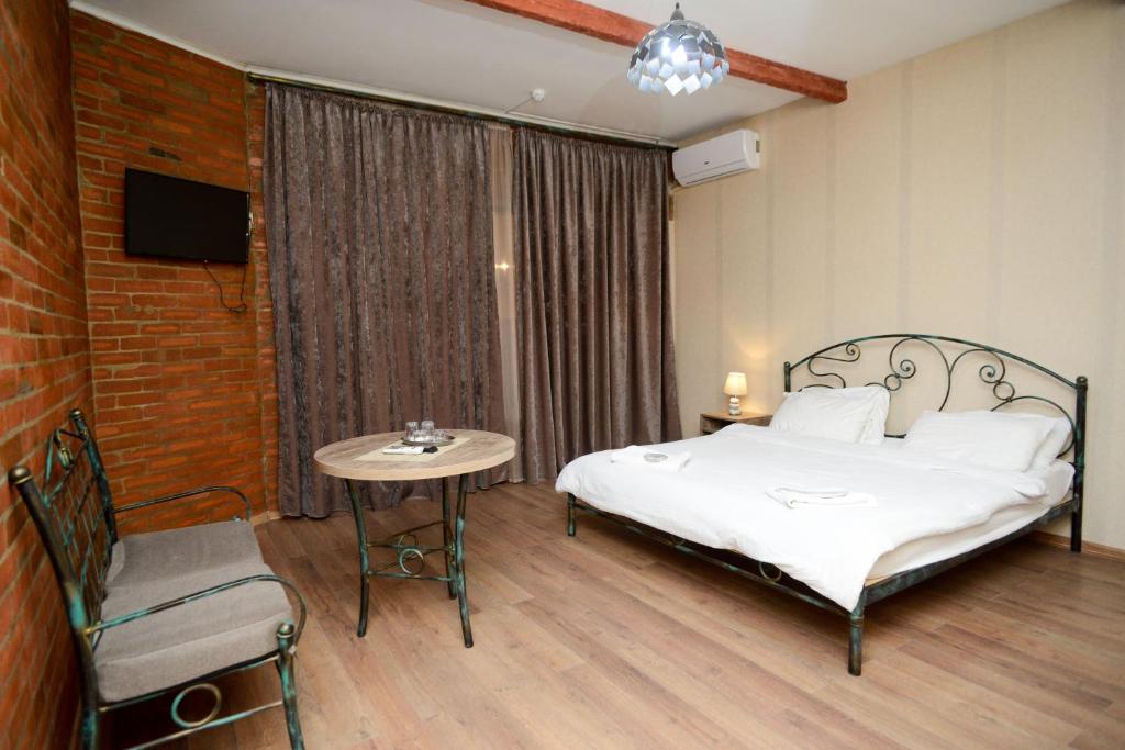 a bedroom with a bed and a table and a tv at Hotel Ragnar in Nizhnyaya Alekseyevka