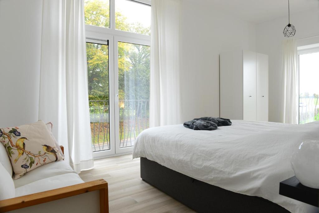 a white bedroom with a bed and a large window at Robert in Huy