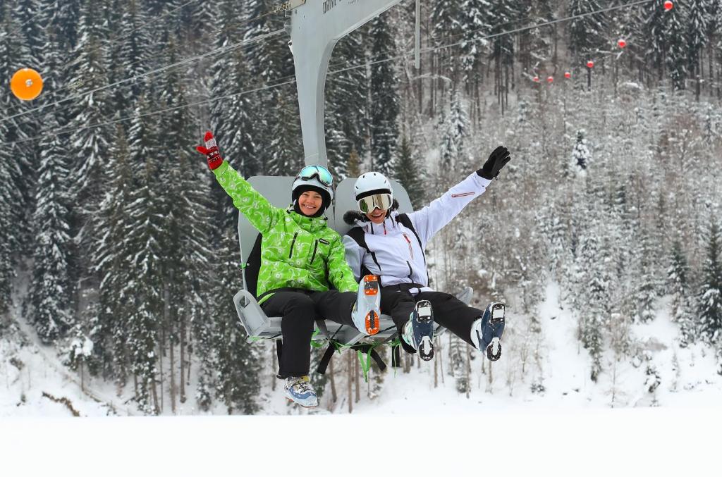 two people sitting on a ski lift in the snow at Bukovel Hotel in Bukovel