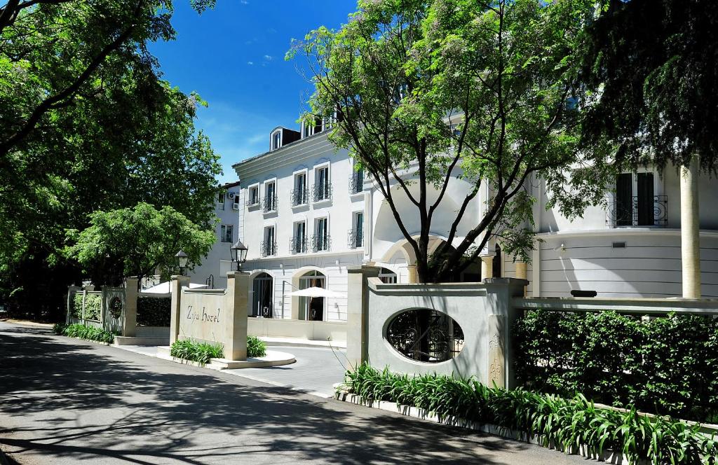 un edificio blanco con un árbol delante en Hotel Ziya, en Podgorica