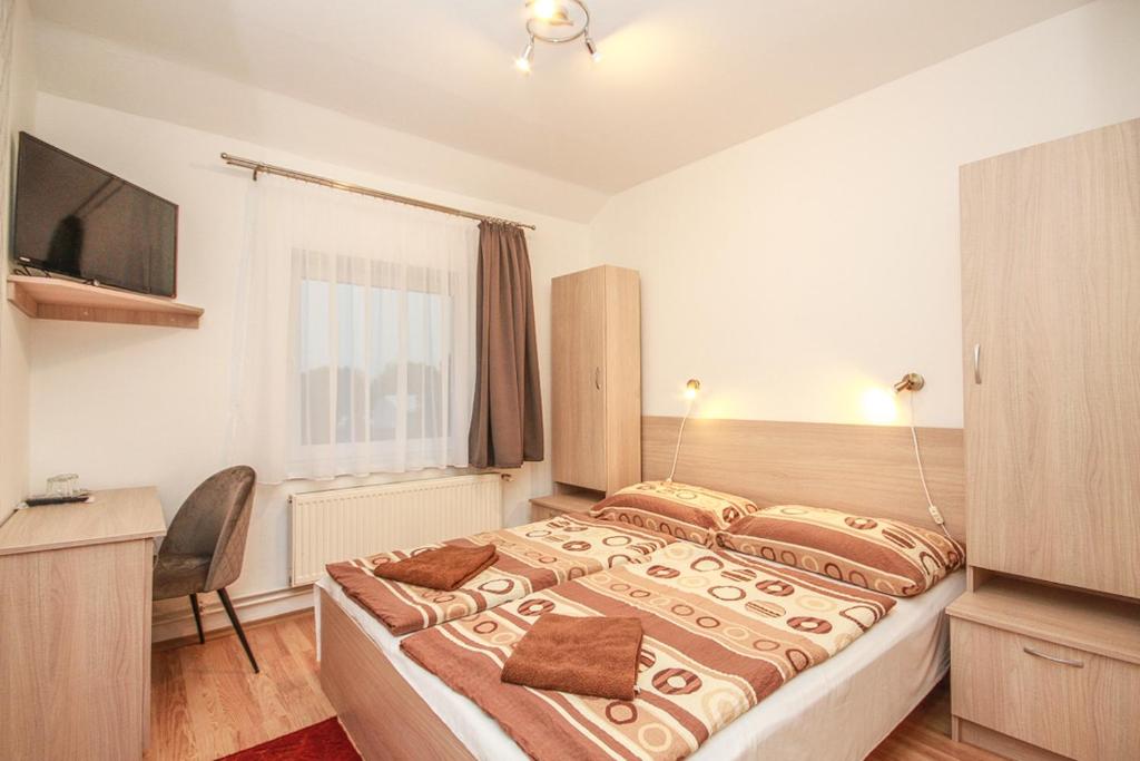 ein Schlafzimmer mit einem großen Bett und einem TV in der Unterkunft Gerendas Panzió in Szombathely
