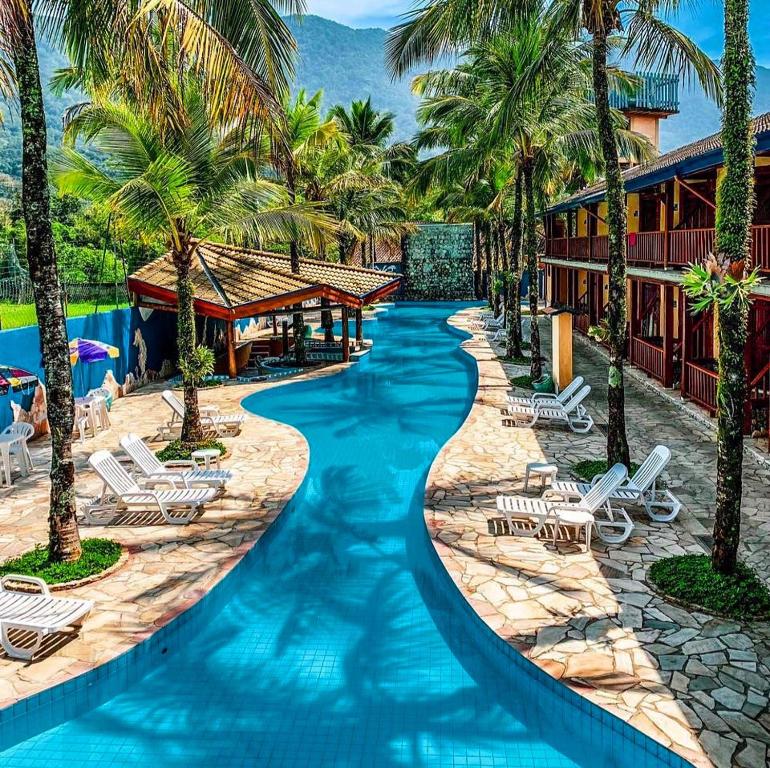 einen Pool in einem Resort mit Palmen in der Unterkunft Pousada Tambayba in Maresias