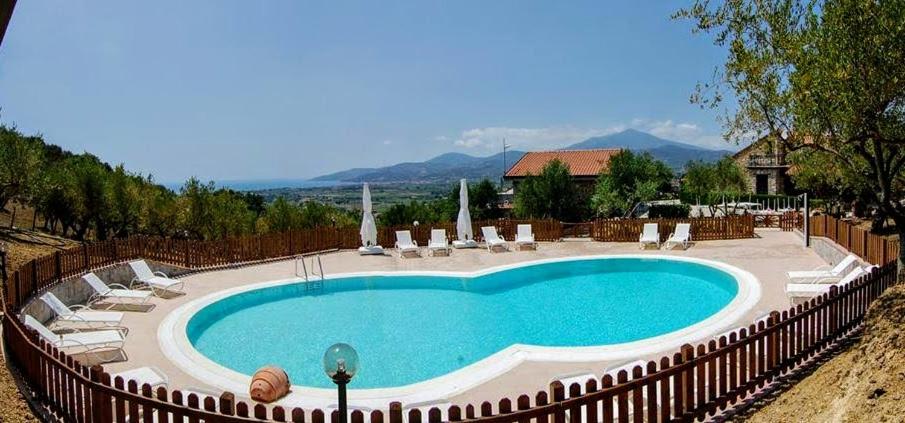 a large swimming pool with chairs and a fence at Agriturismo Tempa del Niglio in Ascea