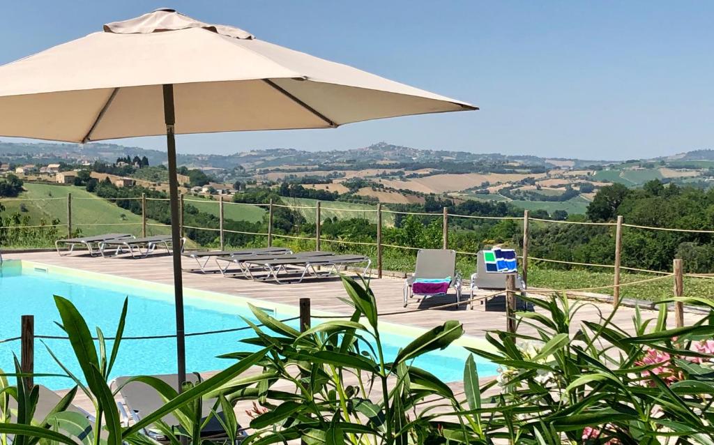 a pool with an umbrella and chairs and a table at Agriturismo Unico Senso - Glamping in Montottone