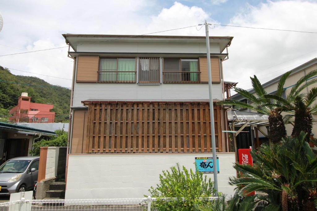 a house with wooden shutters on the side of it at Guest House Aman in Amami