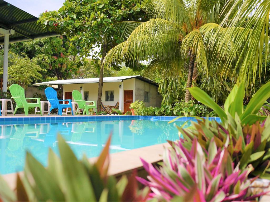 un complexe avec une piscine bordée de chaises et de palmiers dans l'établissement Hospedaje Soma Ometepe Hotel, à Moyogalpa