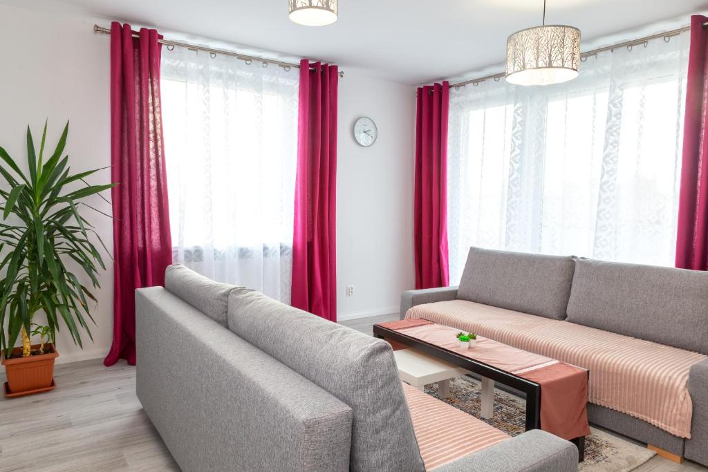 salon z 2 kanapami i czerwonymi zasłonami w obiekcie Apartament Yooka w Szczecinie