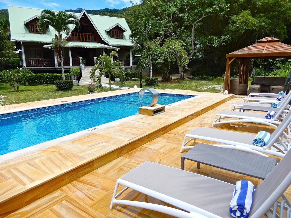 a swimming pool with lounge chairs next to a house at Villa Pasyon in La Digue