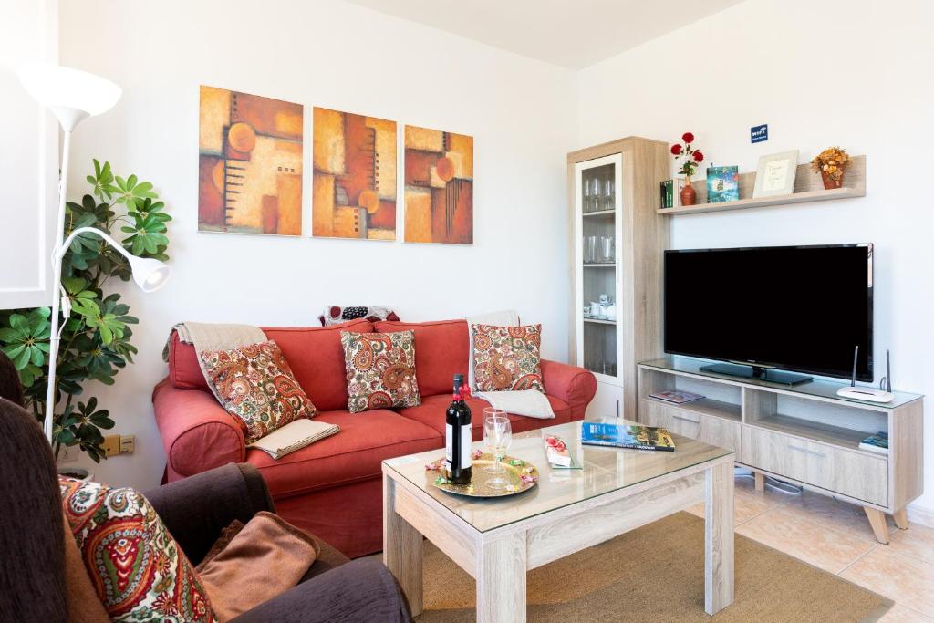 a living room with a red couch and a tv at Vivienda vacacional La Laguna Deluxe 9 in Las Lagunas