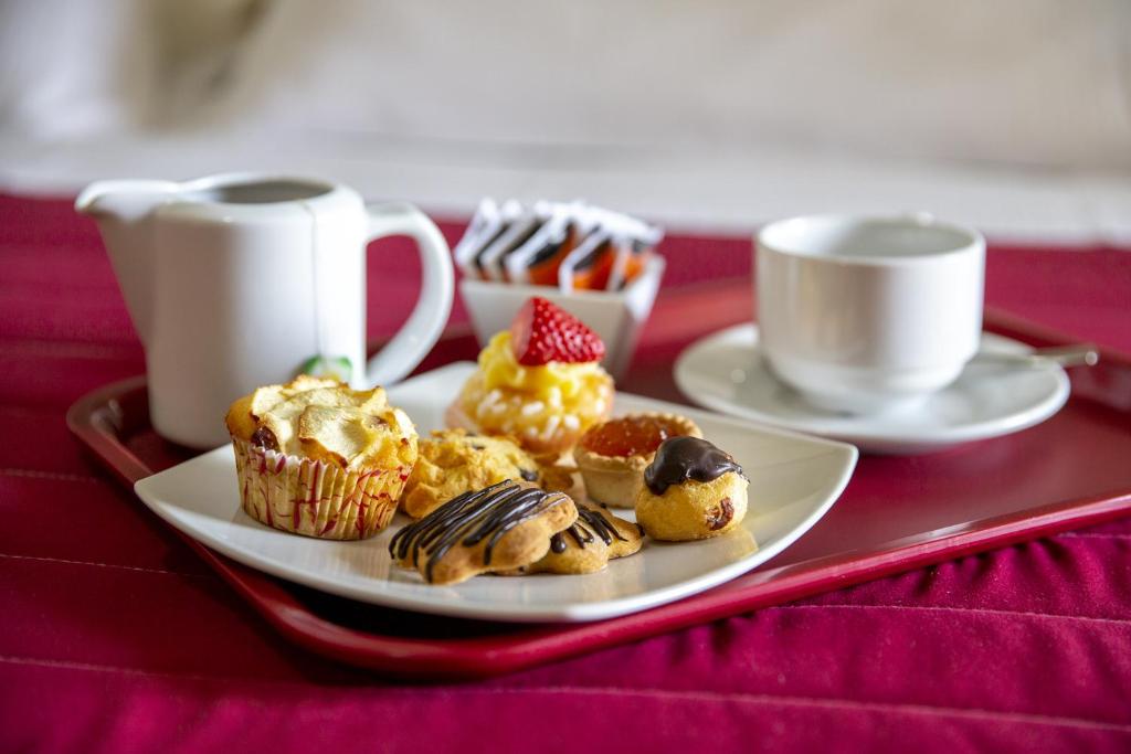 einen Teller Muffins und Tassen Kaffee auf dem Tisch in der Unterkunft Santa Caterina Hotel & Bike in Chianciano Terme