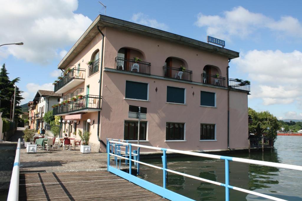 ein Gebäude auf dem Wasser neben einem Dock in der Unterkunft Albergo Ristorante Punta Dell'Est in Clusane sul Lago