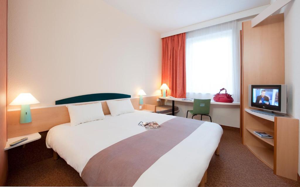 Habitación de hotel con cama grande y TV en ibis Luxembourg Sud, en Livange