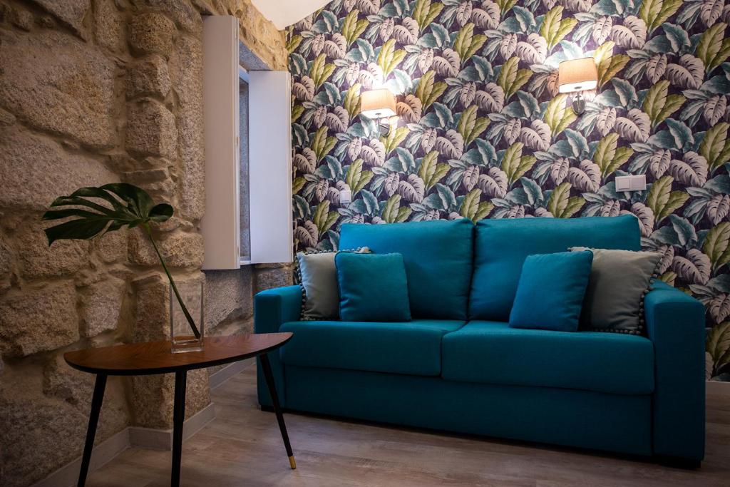 a blue couch in a living room with a floral wallpaper at Casa Jardim By Alojamento Ideal in Porto