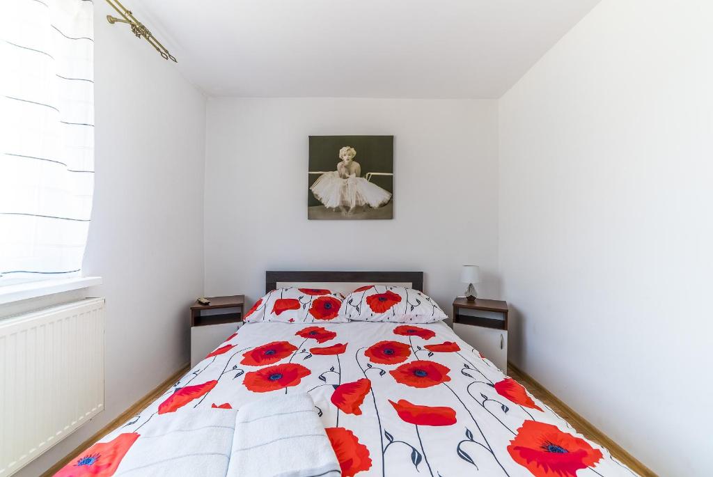a bedroom with a bed with red flowers on it at Pokoje gościnne u Brodzi in Władysławowo