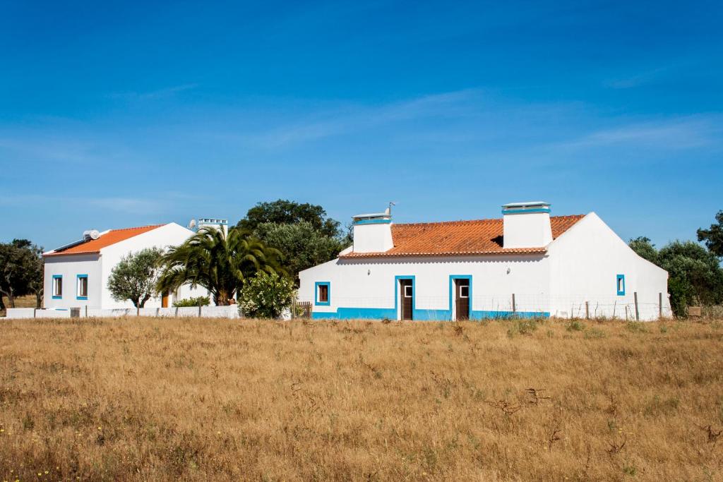 une maison blanche avec des parures bleues dans un champ dans l'établissement Montadinho Houses, à São Bartolomeu da Serra