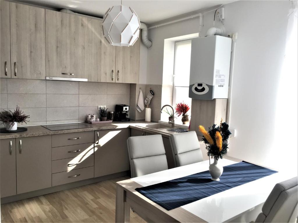 a kitchen with white cabinets and a table with chairs at Luxury Mountain View Apartment in Braşov