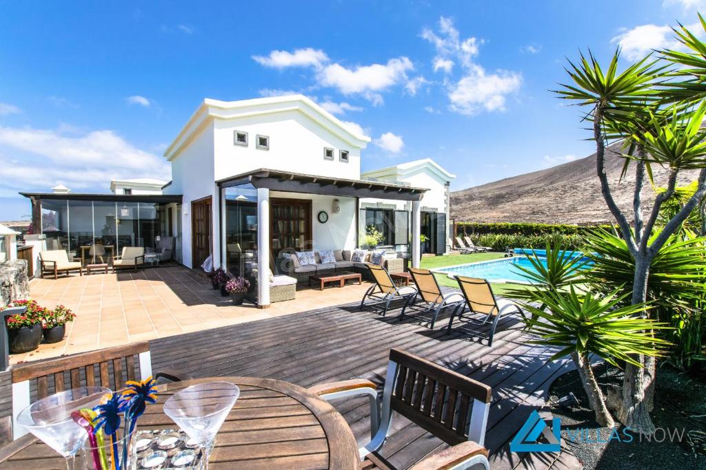 a house with a deck with chairs and a pool at Casa Braeside - LH204 By Villas Now Ltd in Playa Blanca