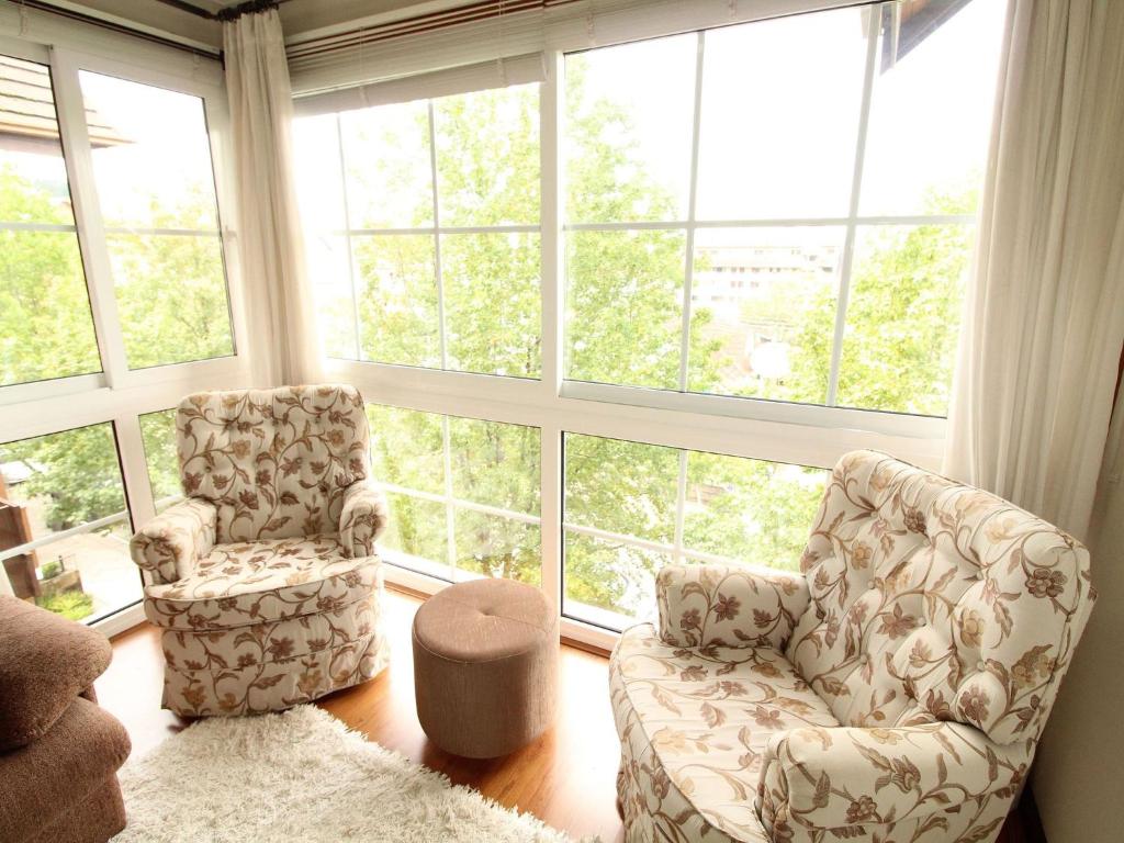 een woonkamer met 2 stoelen en grote ramen bij Villa Di Pietro - 404 in Gramado