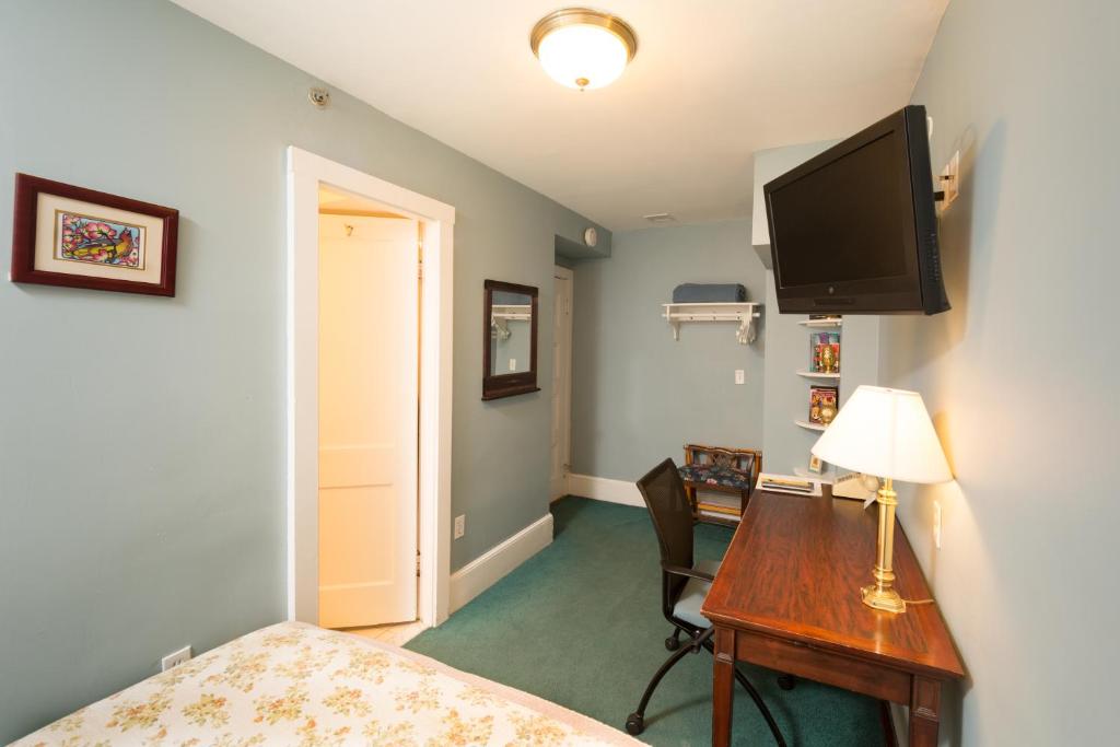 een slaapkamer met een bureau en een televisie aan de muur bij Irving House at Harvard in Cambridge