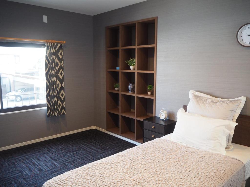 a bedroom with a bed and a clock on the wall at Guest House Bostons / Vacation STAY 5142 in Niigata