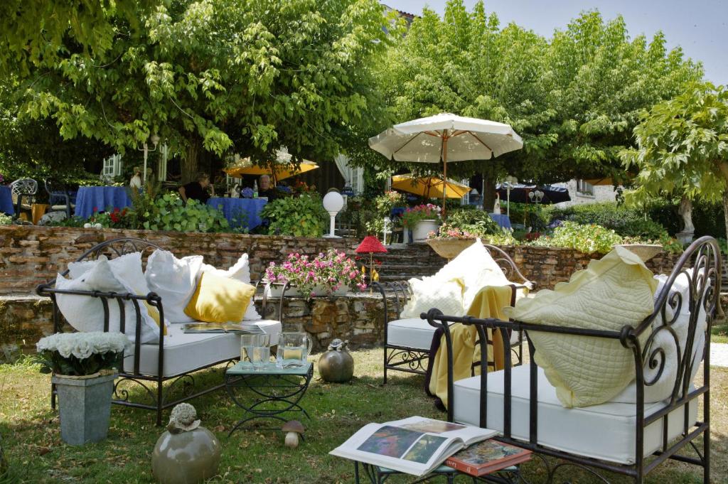 un grupo de sillas con almohadas y sombrilla en Hostellerie Saint-Jacques en Saint-Saud-Lacoussière